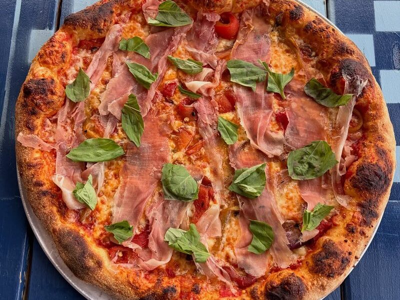 Pizza with charred and pickled banana peppers, prosciutto and basil